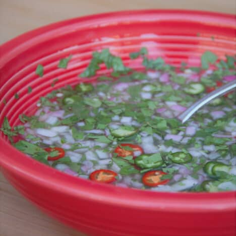 A red bowl filled with the dressing used on the cooked Mexican oysters.