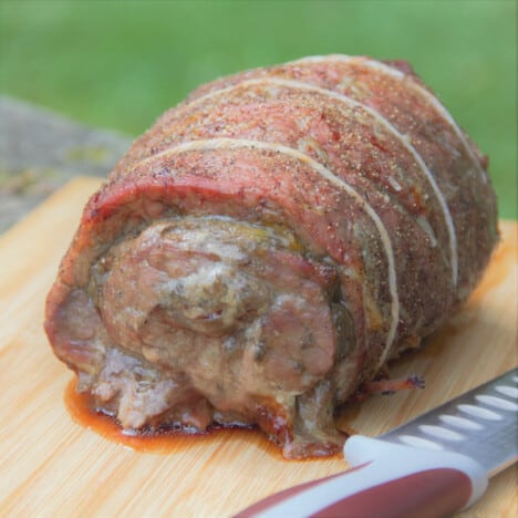 A smoked sage and onion beef roulade sits on a wooden cutting board.