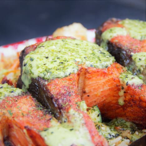 A piece of blackened grilled salmon topped with a green sauce.