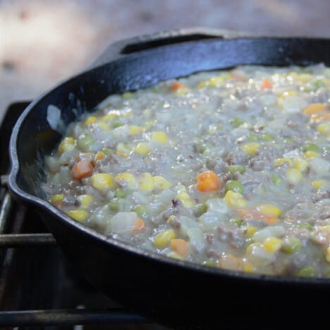 A cast iron skillet with the beef and vegetable casserole simmering inside.