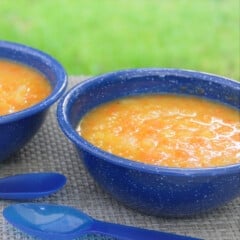 Two bowls of autumn vegetable soup served in blue camp bowls.
