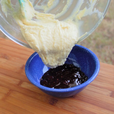 Pudding batter being poured into a blue camp bowl.