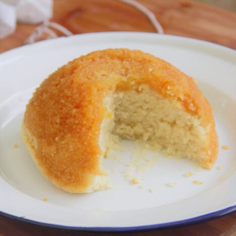 A golden syrup steamed pudding with a quarter serving removed.