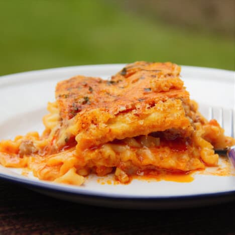 A plate with a fresh serving of lasagna that is sagged and the layers spreading on the plate.