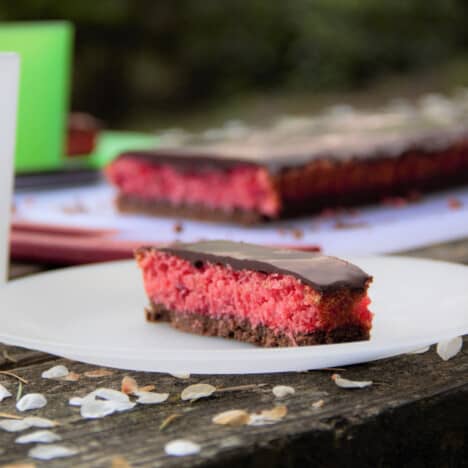 A thin piece of cherry slice is served on a plate with the remaining full slice in the background.