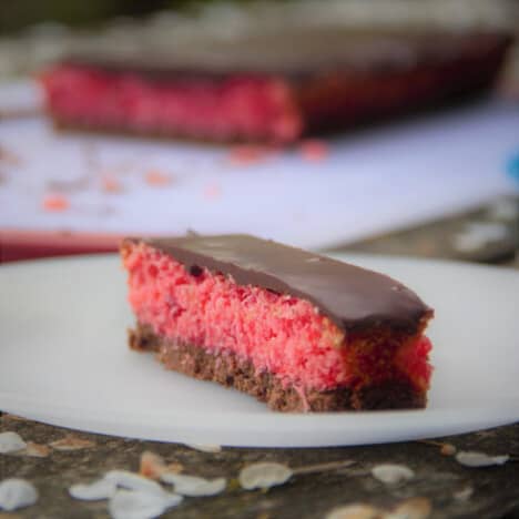 A close up of the cherry slice showing the chocolate base layer, cherry filling, and chocolate top. The remaining full slice is in the background.