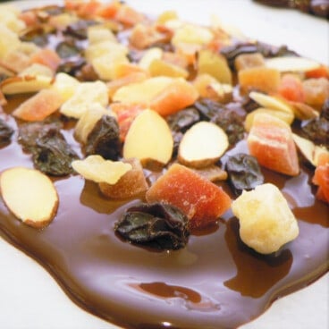 Close ou on melted chocolate on parchment paper with trail mix sprinkled over it.