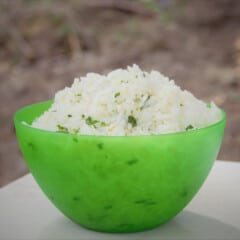 A green serving bowl is filled with cilantro lime rice.
