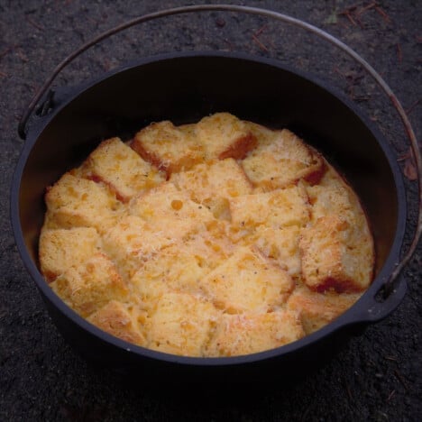 A Dutch oven containing golden brown and chunky corn pudding, fully baked and ready to serve.