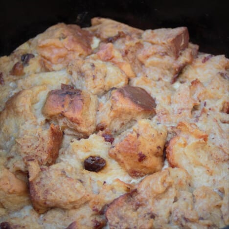 A close up of golden brown hot cross bun bread and butter pudding in a Dutch oven.