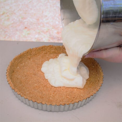 Pouring the cheesecake base into a cookie crumb crust in pie tin.