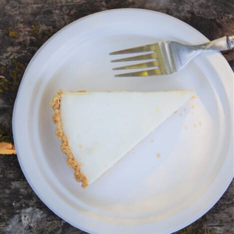 Looking down onto a single slice of no-bake lemon cheesecake on a white plate with a fork.