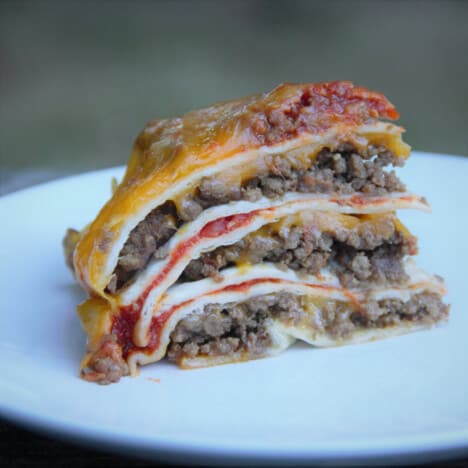 A slice of the tortilla lasagna with well defined lines of the taco style ground beef, salsa, cheese, and tortillas.