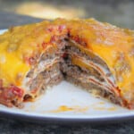 A wedge of the Tortilla lasagna removed, showing the various red, white, and brown layers of the lasagna.