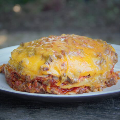 A full mound of a fully cooked Dutch oven tortilla lasagna on a plate ready to be served.