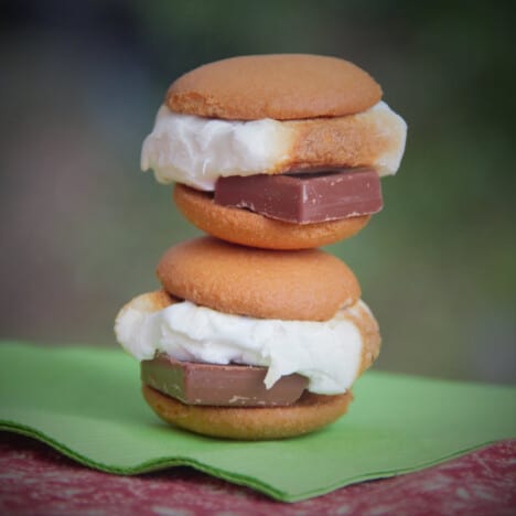 Two vanilla cookie smores, one stacked upon the other on a green napkin.