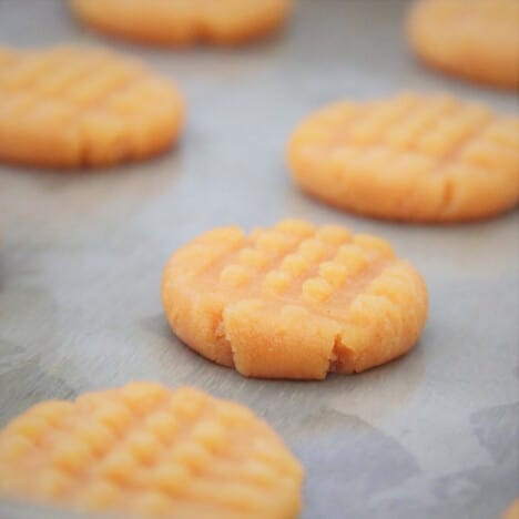 Close up view of an uncooked cookie after it has had the fork crisscross done.