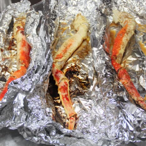 Three cooked crab legs all in individual foil packs.