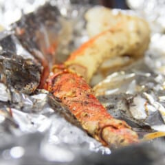 A single cooked crab leg sitting in the foil it was cooked in.