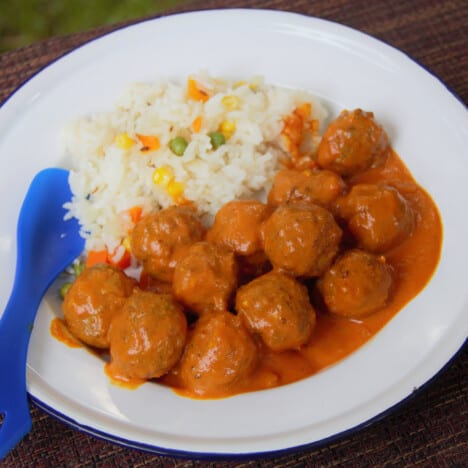 A camp plate with a serving of Indian Meatball Tikka Masala Curry with a side of vegetable rice.
