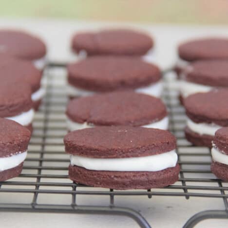 A cooling rack lined with peppermint cream filled chocolate cookie sandwiches.