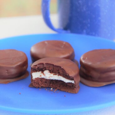 Four peppermint creams on a blue camp plate with one in half exposing the cream filling.