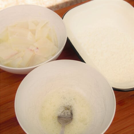 Three bowls containing the squid, egg whites, and salt and pepper mix.