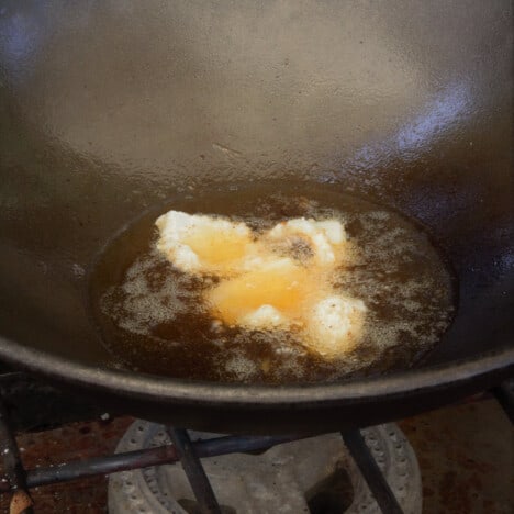 Small batch of four pieces of squid being fried in a wok.