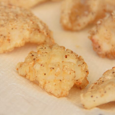 Close up of pieces of salt and pepper squid resting on paper towel before serving.