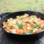 Photo of a skillet filled with butternut squash and bacon stuffing, garnished with parsley and ready to serve.