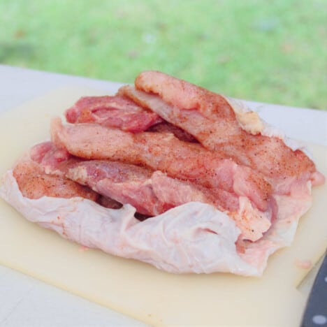 Raw turkey breast and thighs are sitting on the turkey skin ready to be rolled.