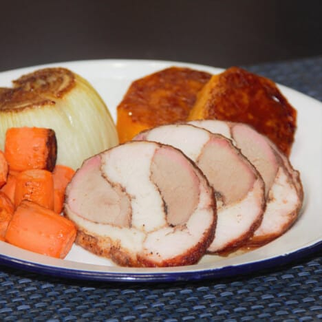 Three slices of the smoked turkey roll are served on a camp plate with a range of roasted vegetables.