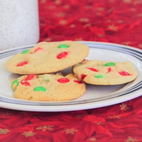Three soft and chewy Christmas cookies are on a white plate on a red napkin ready to eat.