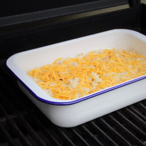 Looking into a white casserole dish sitting on a grill with an unbaked tuna noodle casserole within.