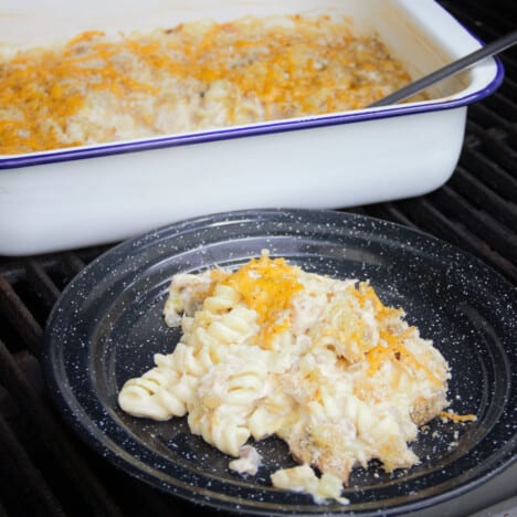 Tuna Casserole is served on a black camp plate with the remaining casserole still in the casserole dish in the background.