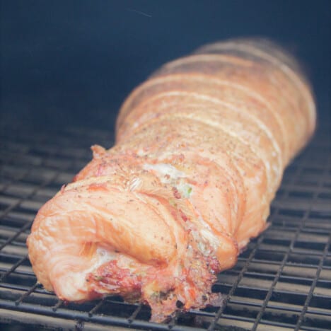A full stuffed turkey breast starting to get a golden brown while cooking in the smoker.