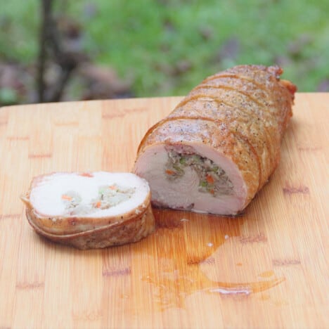 The smoked turkey roll with a slice cut off exposing the stuffing inside.