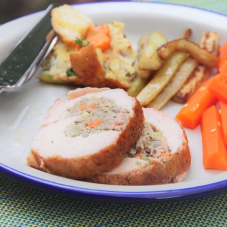Two slices of Turkey Breast with Stuffing with traditional sides on a camp plate.