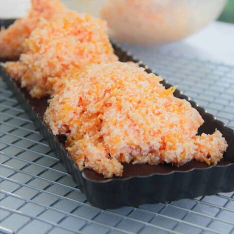 Mounds of the rice apricot filling are piled on top of the cookie base in a baking tin, on top of a cooling rack.