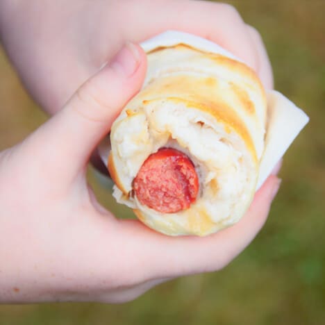 A campfire hotdog with a bite out of it showing the cooked bread and hot dog within.