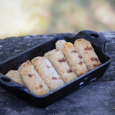 A small rectangle cast iron dish with cooked Mozzarella Sticks ready to eat.