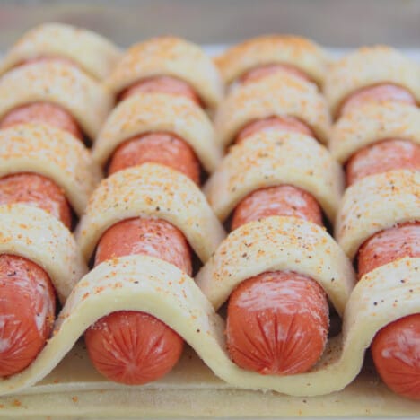 Looking down on a raw hot dog tart showing the pasty weave over the hotdogs.