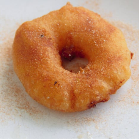 A close up of a cooked, golden brown pineapple fritter topped with the dessert rub.