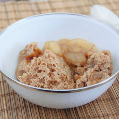 A white camp bowl with a serving of apple spice dump cake.