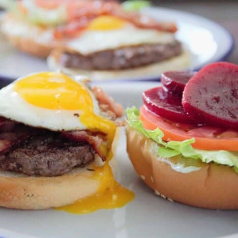 Looking at two sides of a burger: the left is the hot elements including the burger, bacon, and fried egg. The right side is the salad elements including the lettuce, tomato, and beetroot.