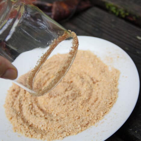 A glass being removed from a side plate of biscuit crumbs having just been rimmed.