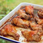 Grilled chicken wings sit in a baking pan with grass in the background.
