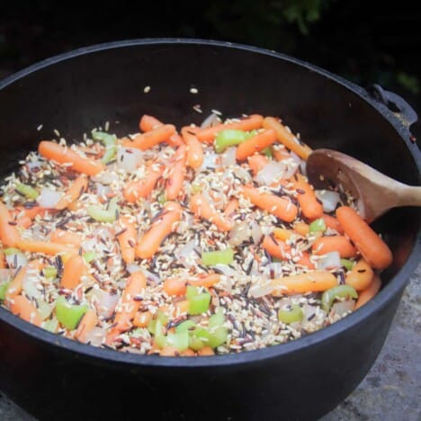 Looking into a Dutch oven with cooking wild rice, celery, and baby carrots.