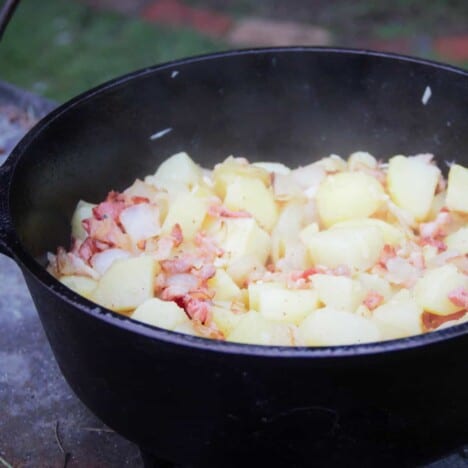 The potatoes have just been added to the bacon and onions in the Dutch oven to be browned.