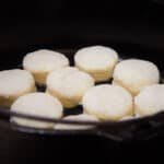 Looking into a Dutch oven filled with raw biscuits ready to be cooked.